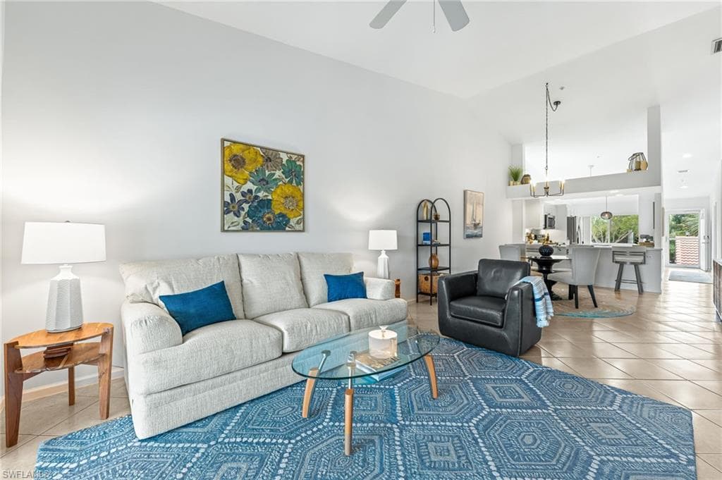 Living area featuring light tile patterned floors, high vaulted ceiling, and ceiling fan