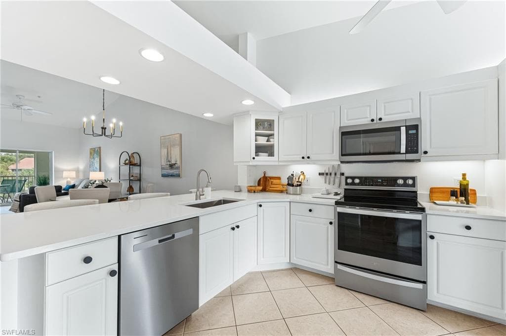 Kitchen featuring a ceiling fan, appliances with stainless steel finishes, glass insert cabinets, open floor plan, and recessed lighting