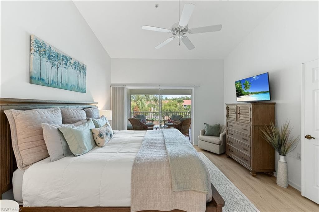 Bedroom with wood finished floors, lofted ceiling, access to exterior, and a ceiling fan