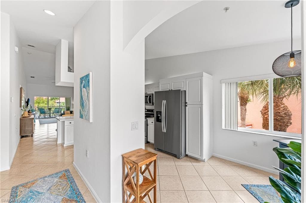 Kitchen featuring appliances with stainless steel finishes, white cabinetry, light tile patterned floors, and arched walkways