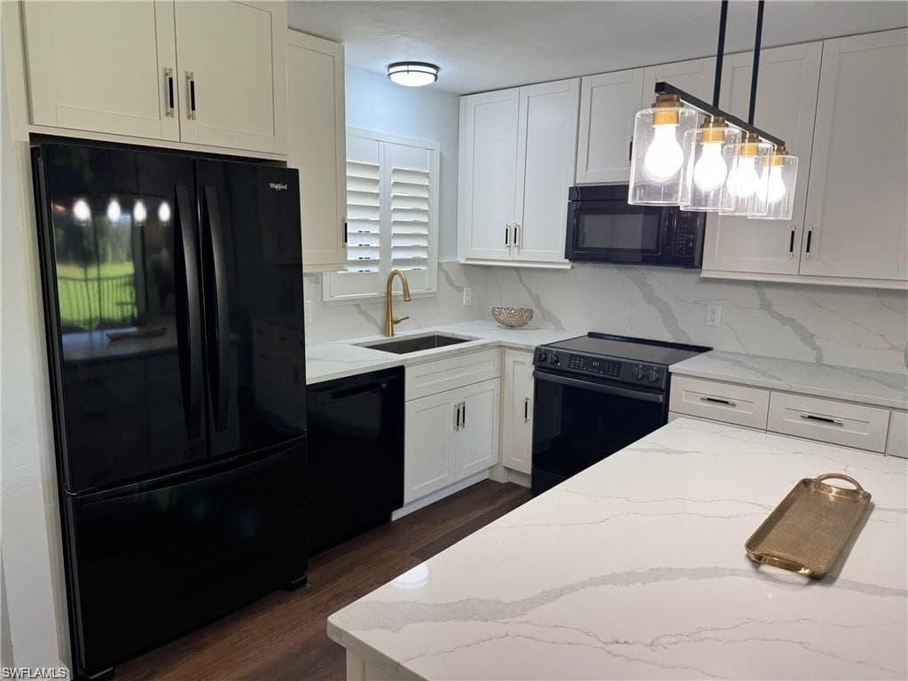 Kitchen featuring black appliances, white cabinets, light stone counters, backsplash, and dark wood-type flooring