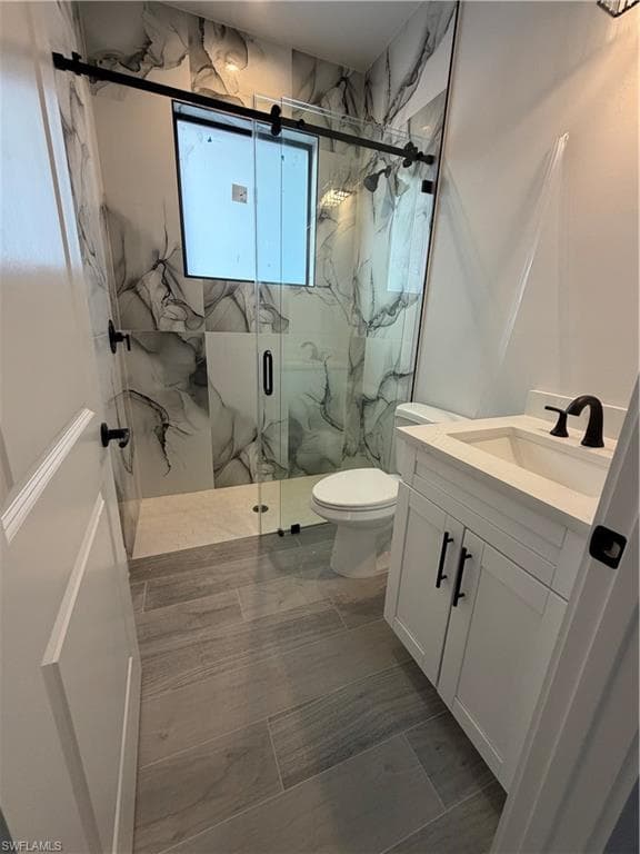 Full bath featuring a marble finish shower and vanity