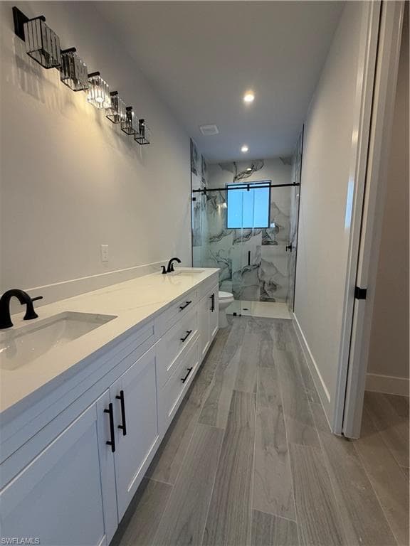 Bathroom featuring double vanity, a marble finish shower, and recessed lighting