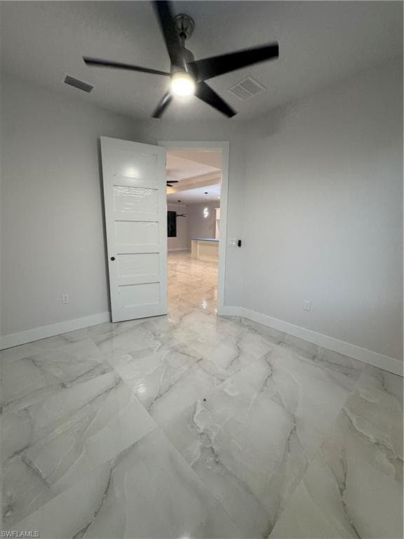 Empty room featuring light marble finish flooring and ceiling fan