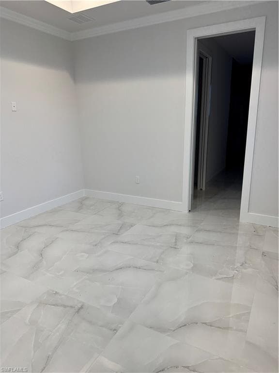 Empty room featuring crown molding and light marble finish flooring