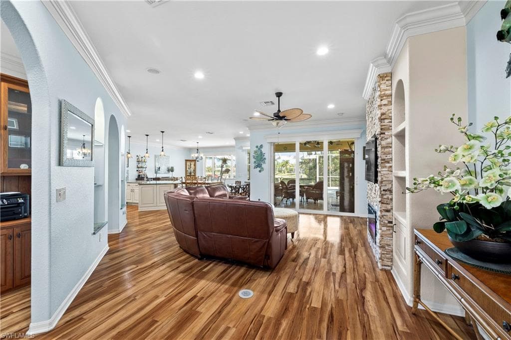 Living room with crown molding, arched walkways, light wood-type flooring, recessed lighting, and ceiling fan