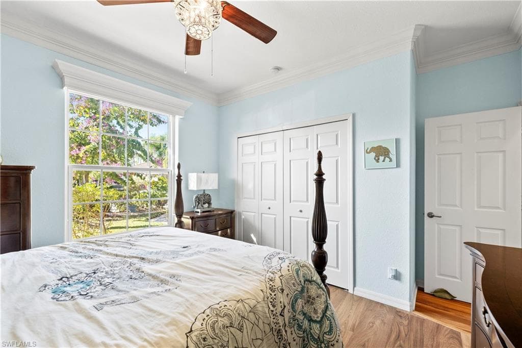Bedroom featuring light wood-style flooring, a closet, ceiling fan, and crown molding