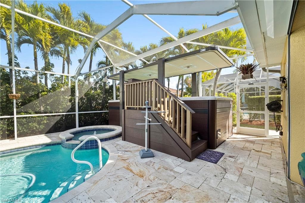 View of swimming pool featuring a sunroom, glass enclosure, a patio area, a pool with connected hot tub, and stairway