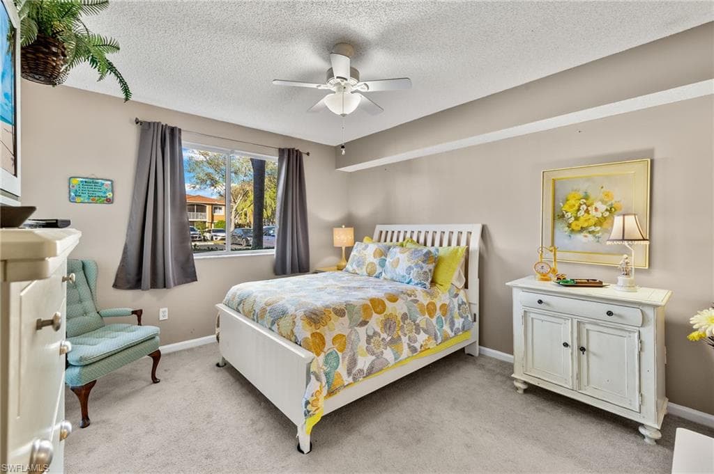 Bedroom featuring light colored carpet, a textured ceiling, and ceiling fan
