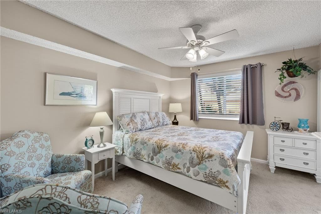 Bedroom with light colored carpet, ceiling fan, and a textured ceiling