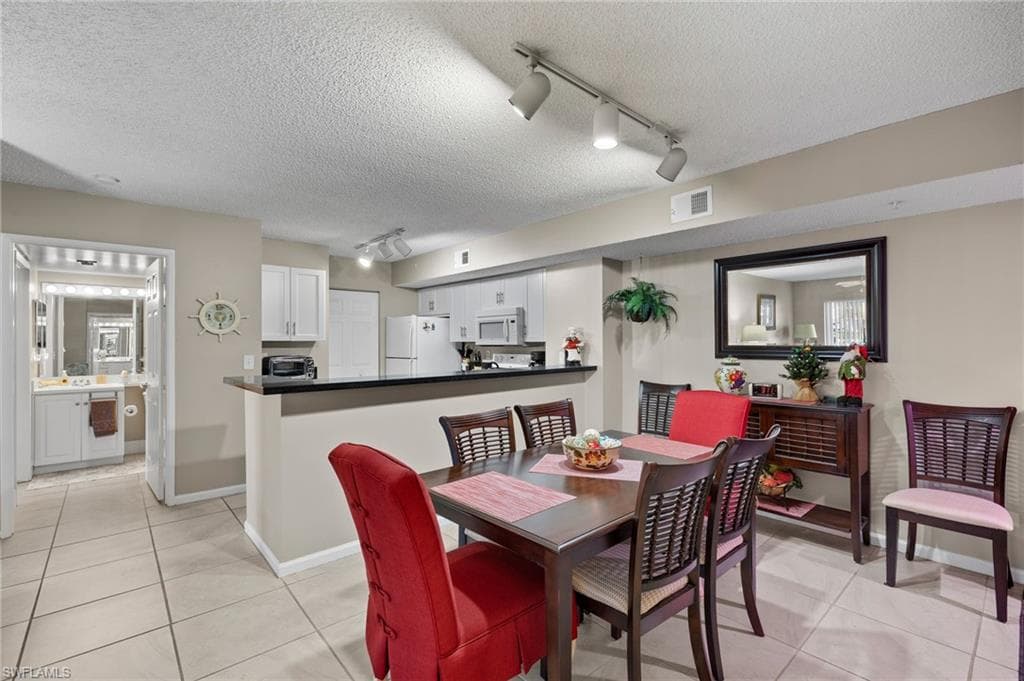 Dining room with rail lighting, light tile patterned floors, and a textured ceiling