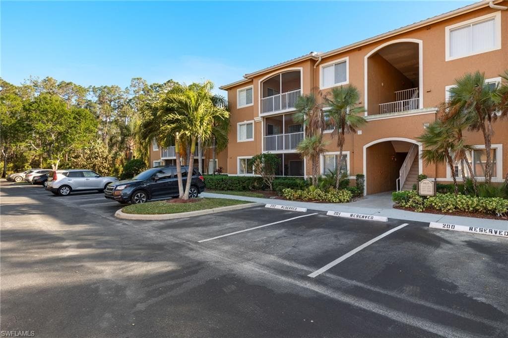View of apartment building / complex featuring uncovered parking