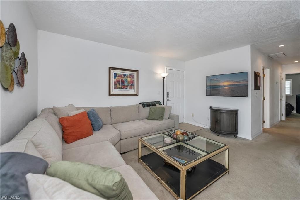 Living room with light colored carpet and a textured ceiling