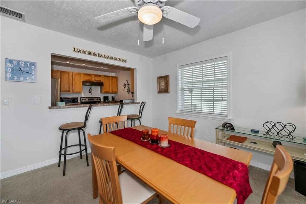 Dining room with light carpet, ceiling fan, and a textured ceiling