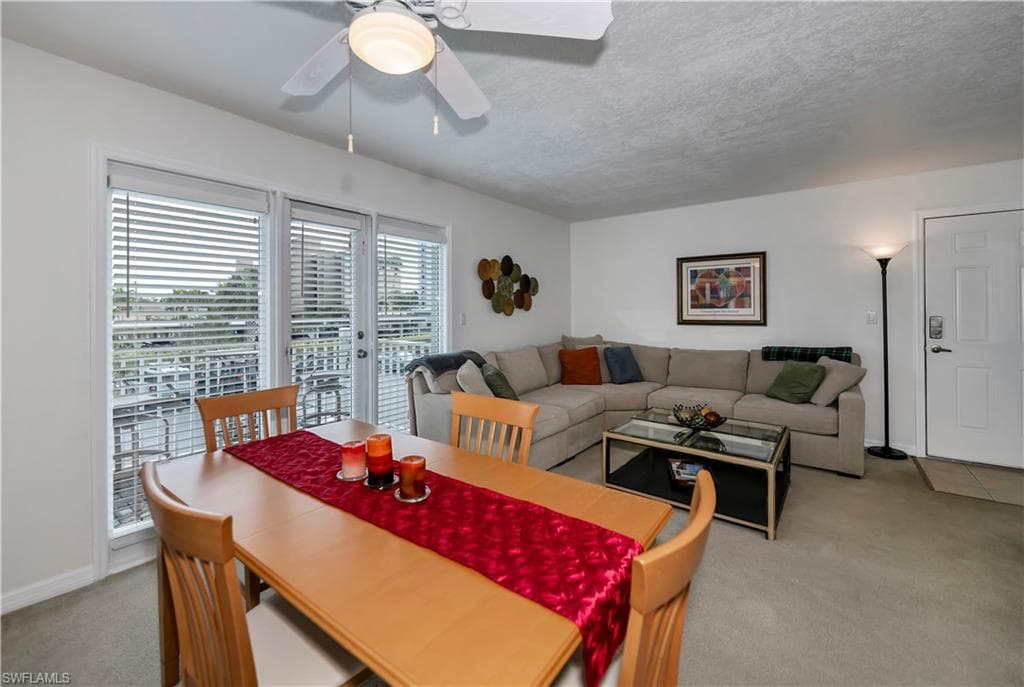Dining area featuring light carpet, ceiling fan, and a textured ceiling