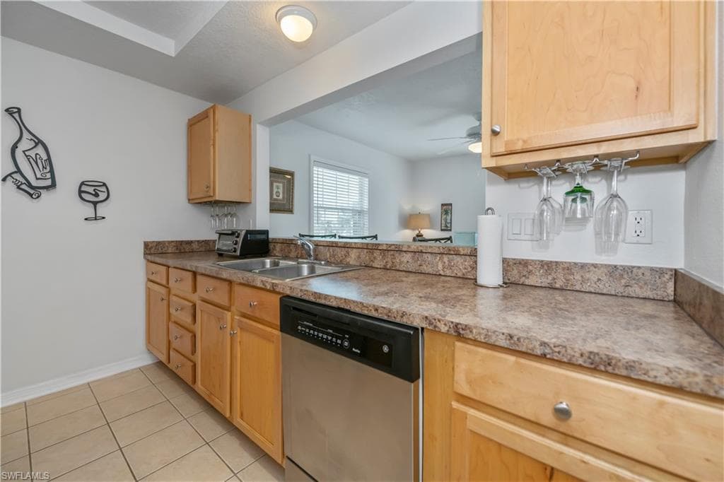 Kitchen featuring dishwasher, light brown cabinetry, sink, light tile patterned flooring, and ceiling fan