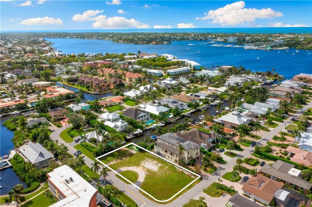 Aerial view of residential area featuring property parcel outlined and a nearby body of water