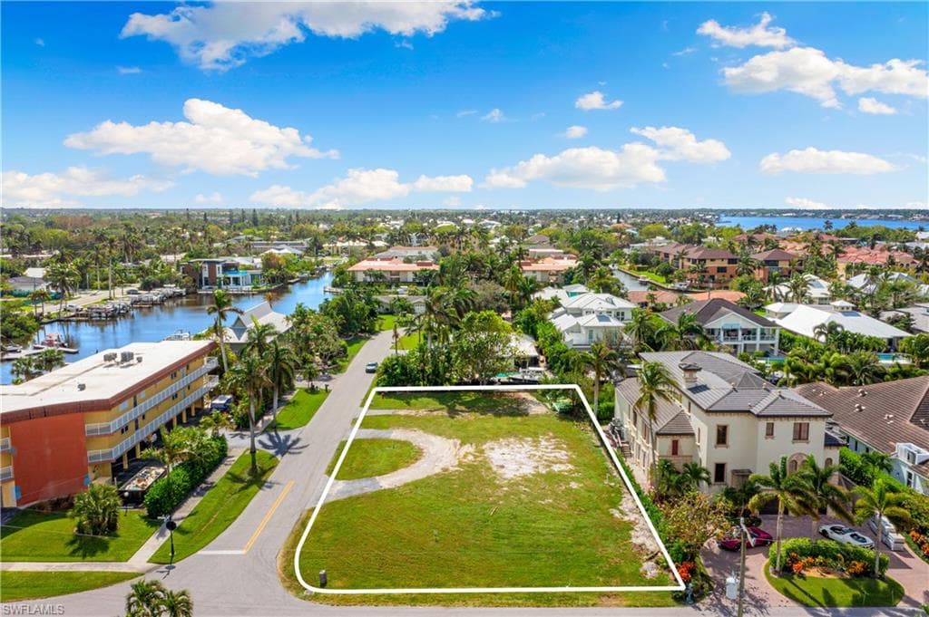 Aerial view of residential area with property boundaries highlighted and a nearby body of water