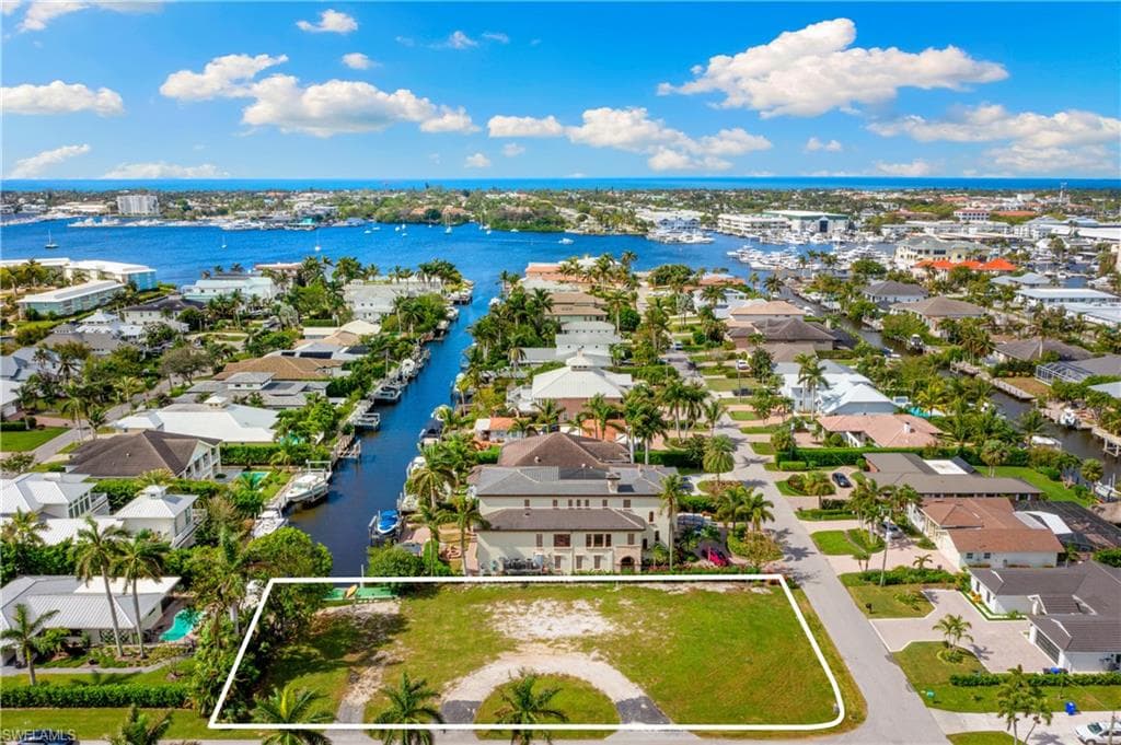 Aerial perspective of suburban area featuring property parcel outlined and a nearby body of water