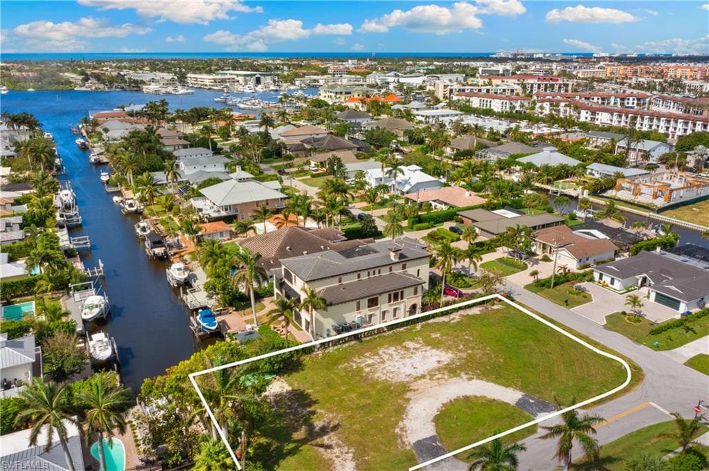 Aerial view of residential area featuring property boundaries highlighted and a nearby body of water