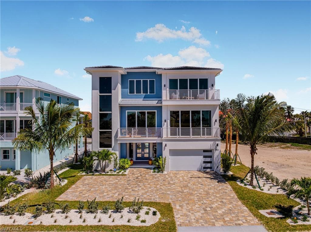 View of front of home with a balcony, decorative driveway, french doors, stucco siding, and a garage