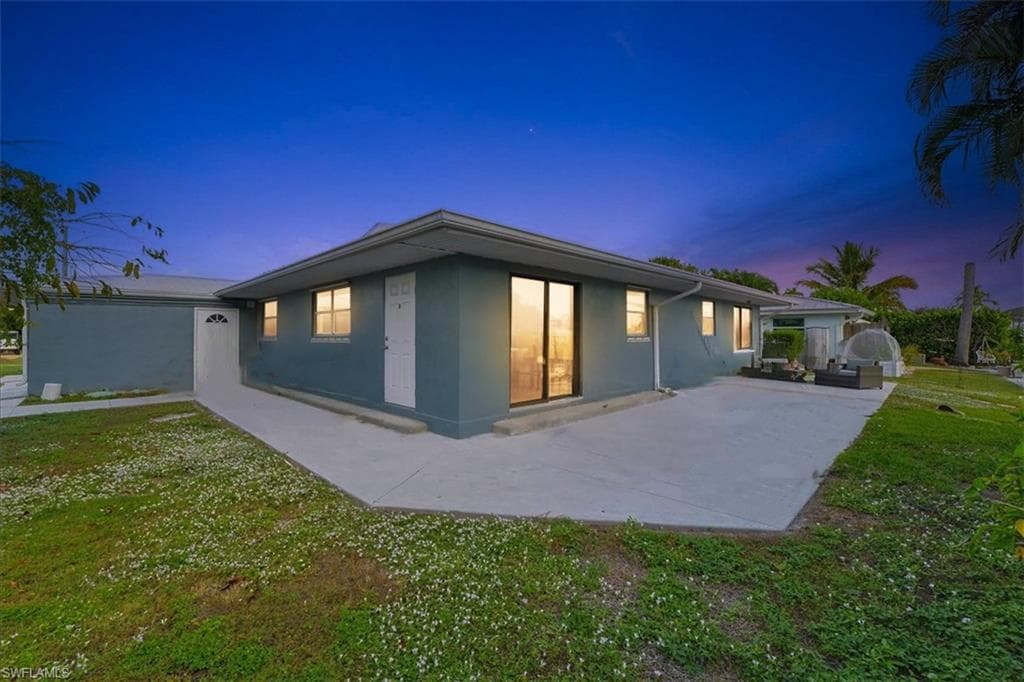 Back of house featuring a lawn, stucco siding, and a patio