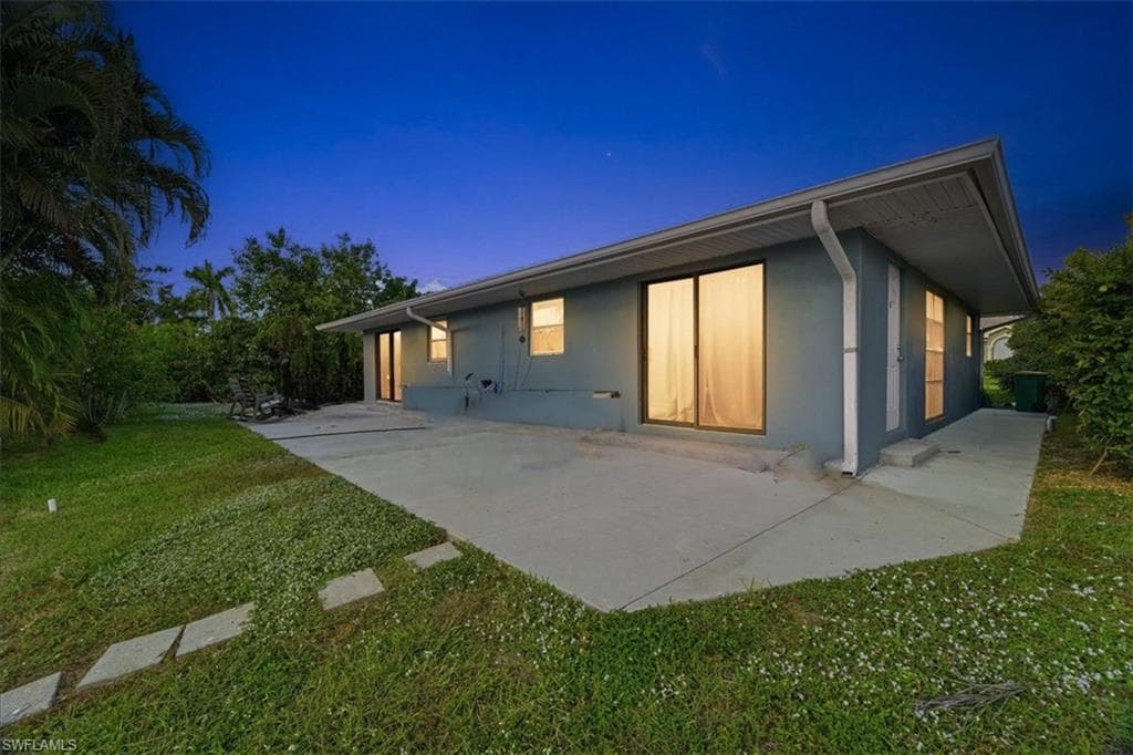 Back of house with a yard, stucco siding, and a patio area