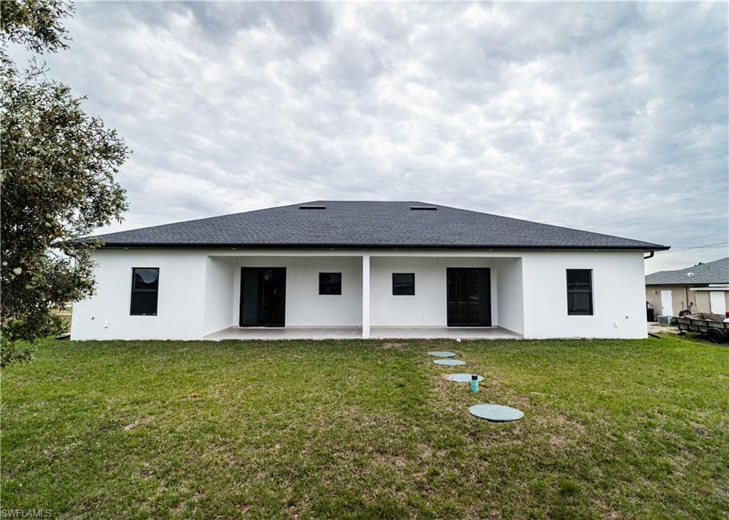 Back of house featuring a patio area, stucco siding, and a lawn