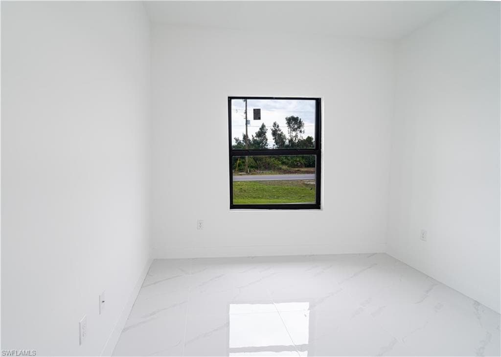 Empty room featuring marble finish flooring and baseboards