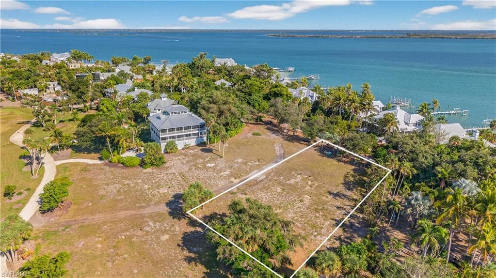 Aerial view of property and surrounding area featuring property parcel outlined and a nearby body of water