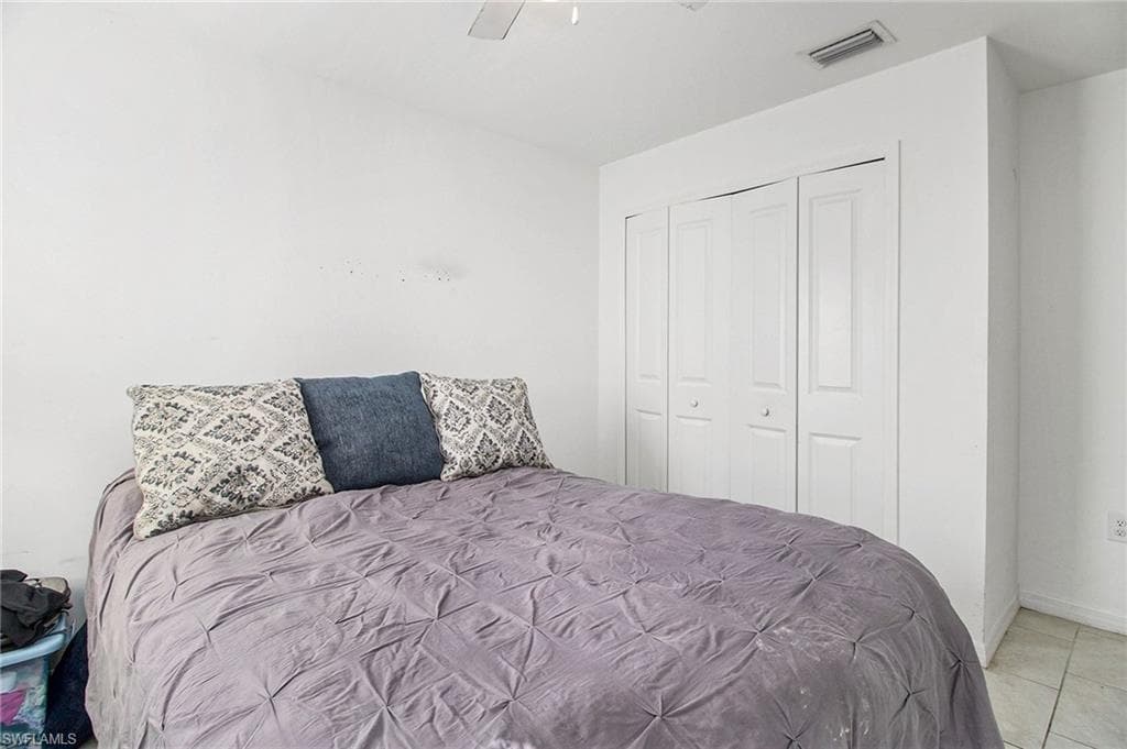 Bedroom featuring a closet, a ceiling fan, and light tile patterned floors
