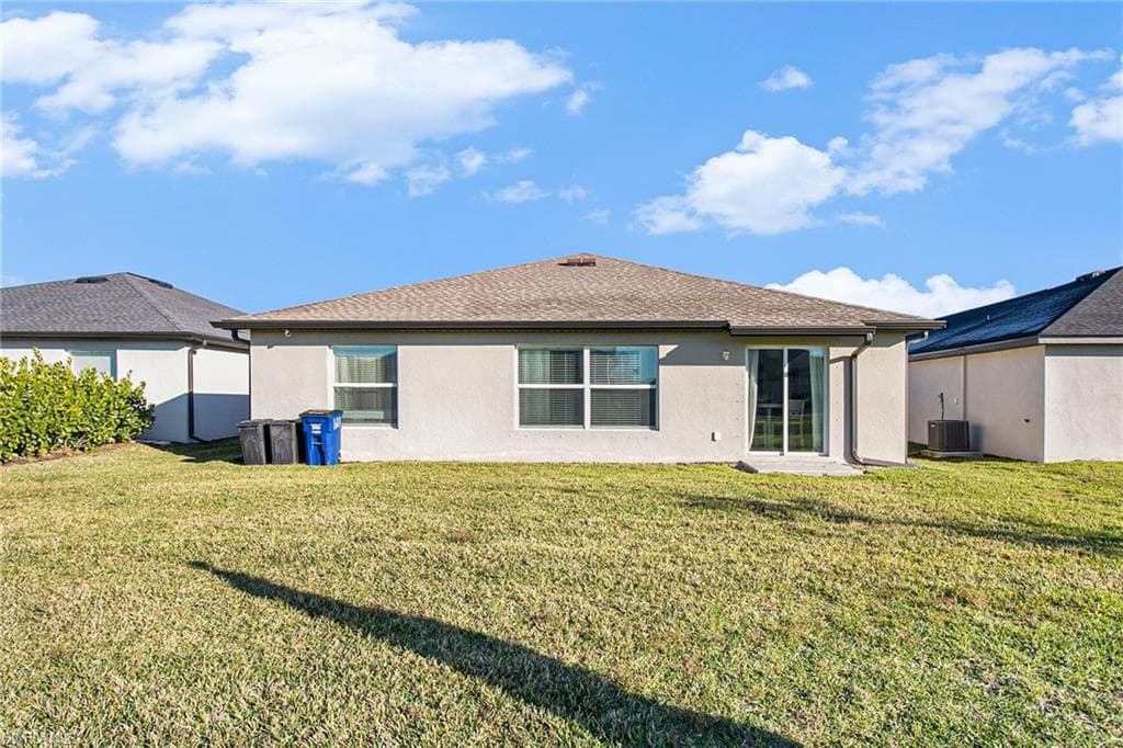 Back of house with a lawn, stucco siding, a shingled roof, and a patio area