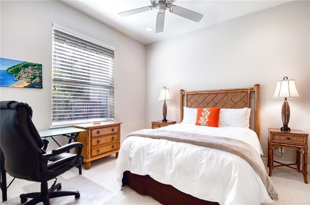 Bedroom featuring an office area, a ceiling fan, and light colored carpet