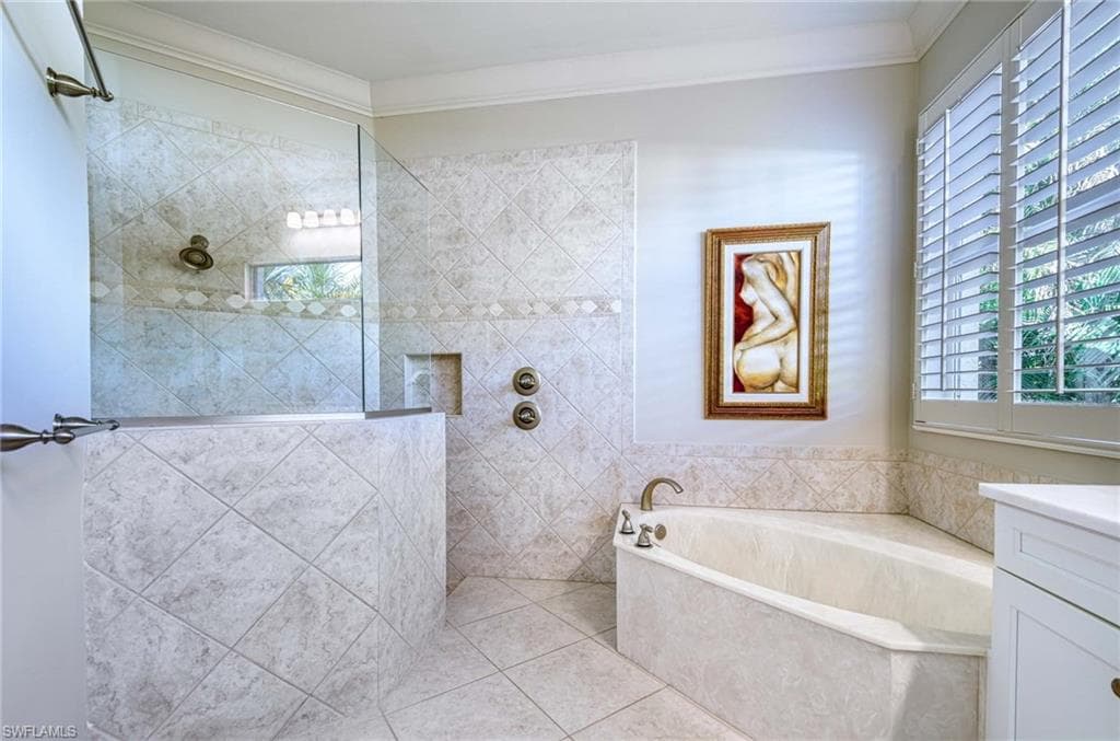Full bathroom with a walk in shower, a garden tub, vanity, ornamental molding, and tile patterned floors