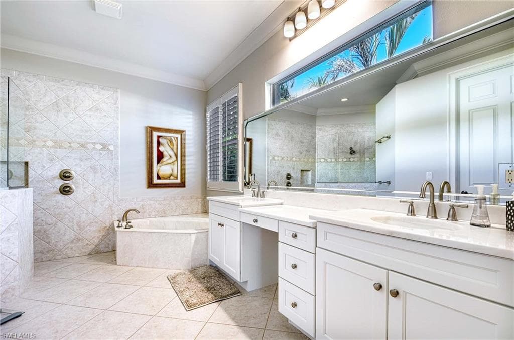 Full bath featuring walk in shower, a garden tub, ornamental molding, double vanity, and light tile patterned floors