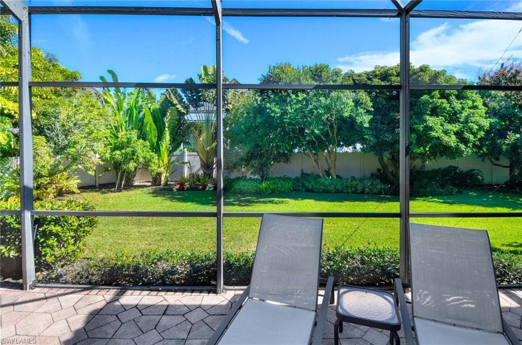 Fenced backyard featuring a sunroom and glass enclosure