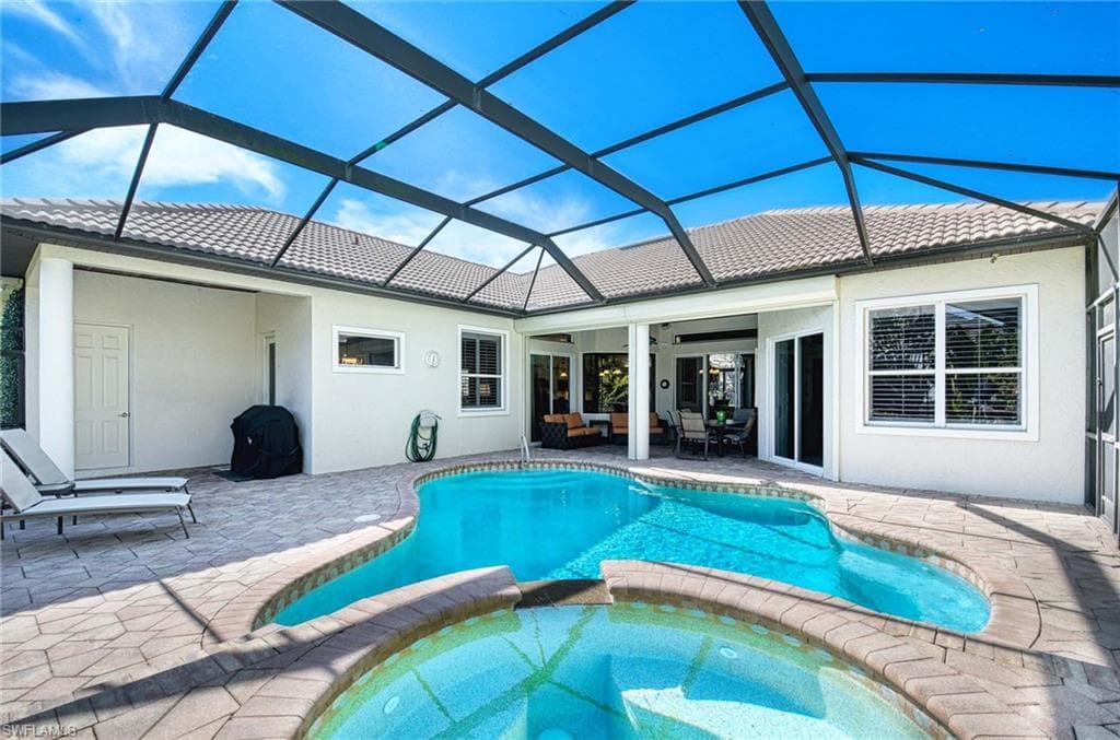 View of swimming pool featuring a patio, a pool with connected hot tub, a lanai, and a sunroom