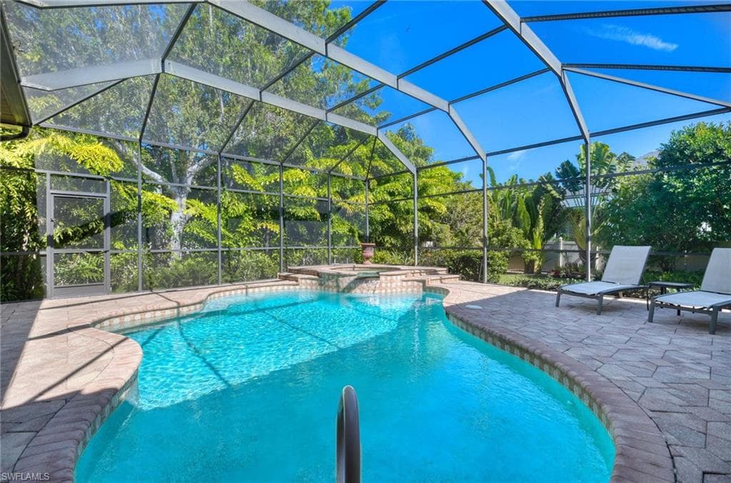 View of swimming pool with a patio area, glass enclosure, a pool with connected hot tub, and a sunroom
