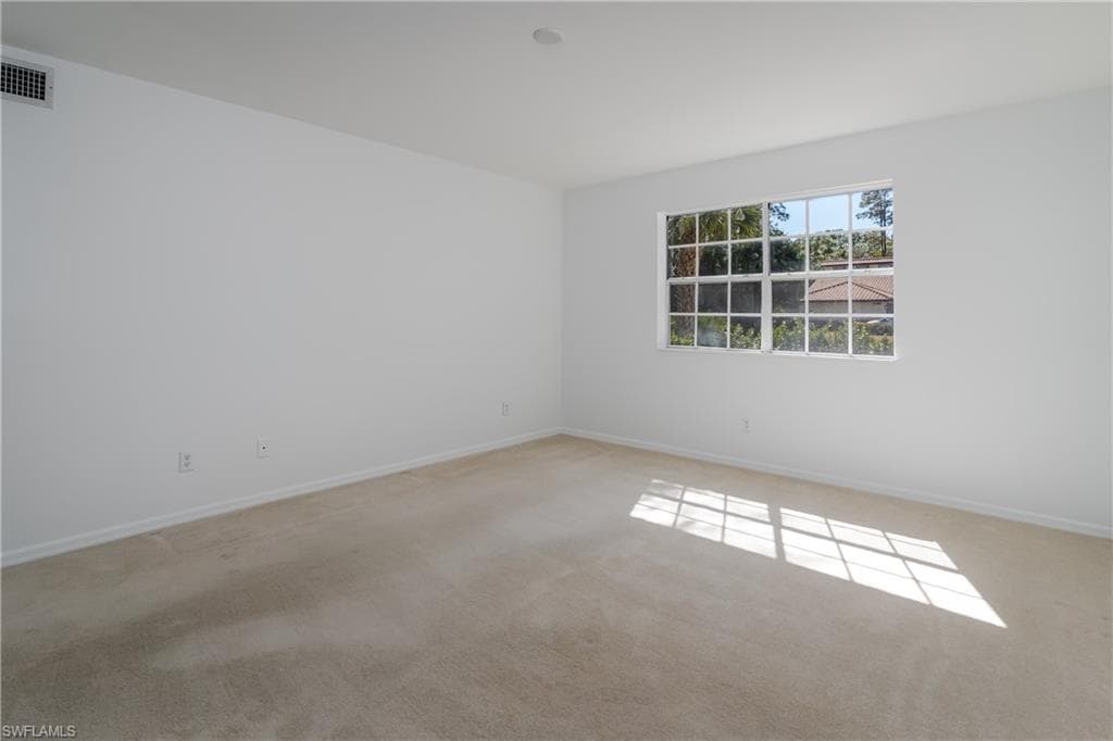 Empty room featuring baseboards and light carpet