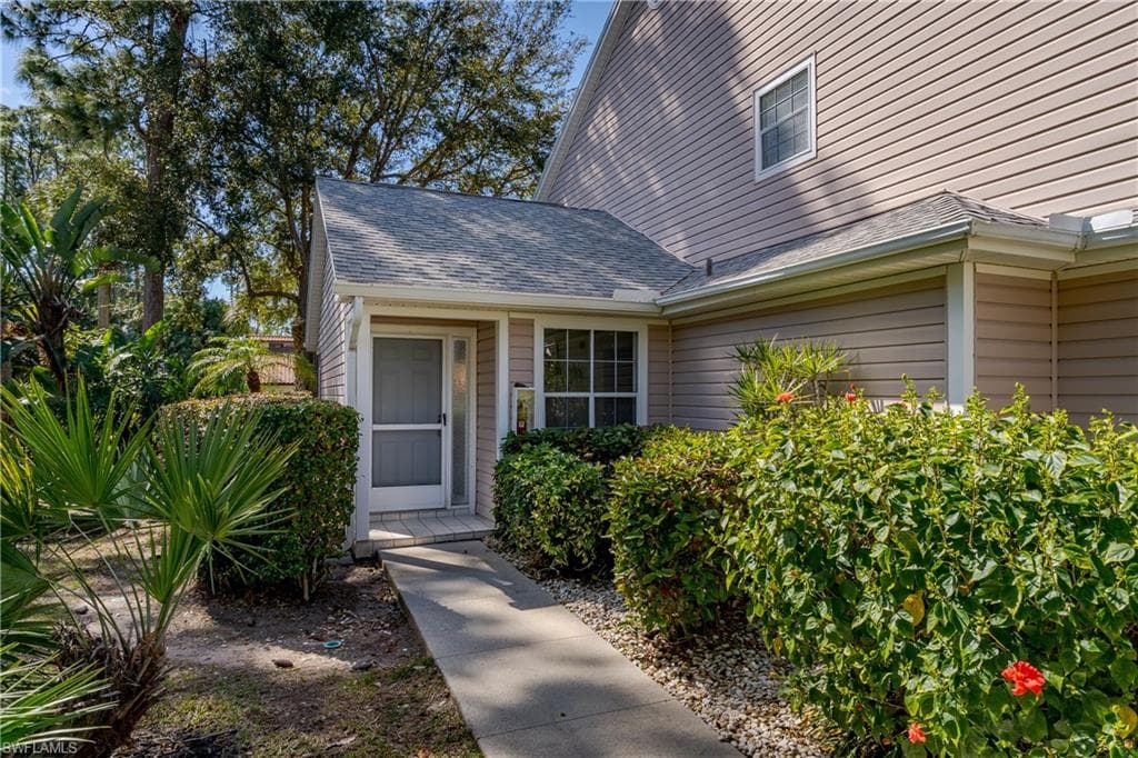 Doorway to property featuring roof with shingles