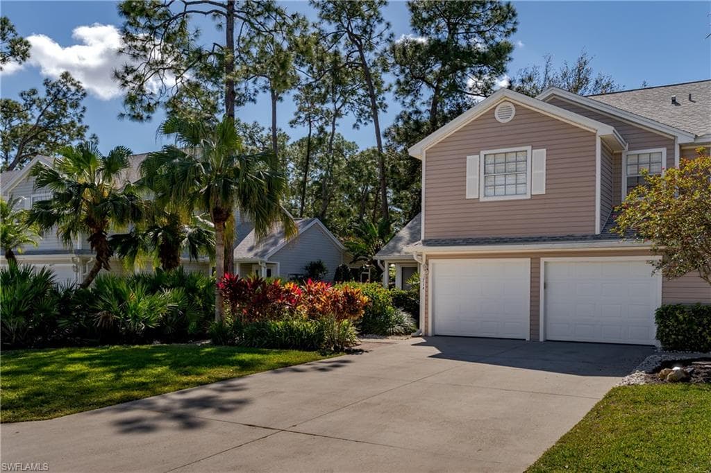 View of front of home with a front yard, an attached garage, driveway, and a shingled roof