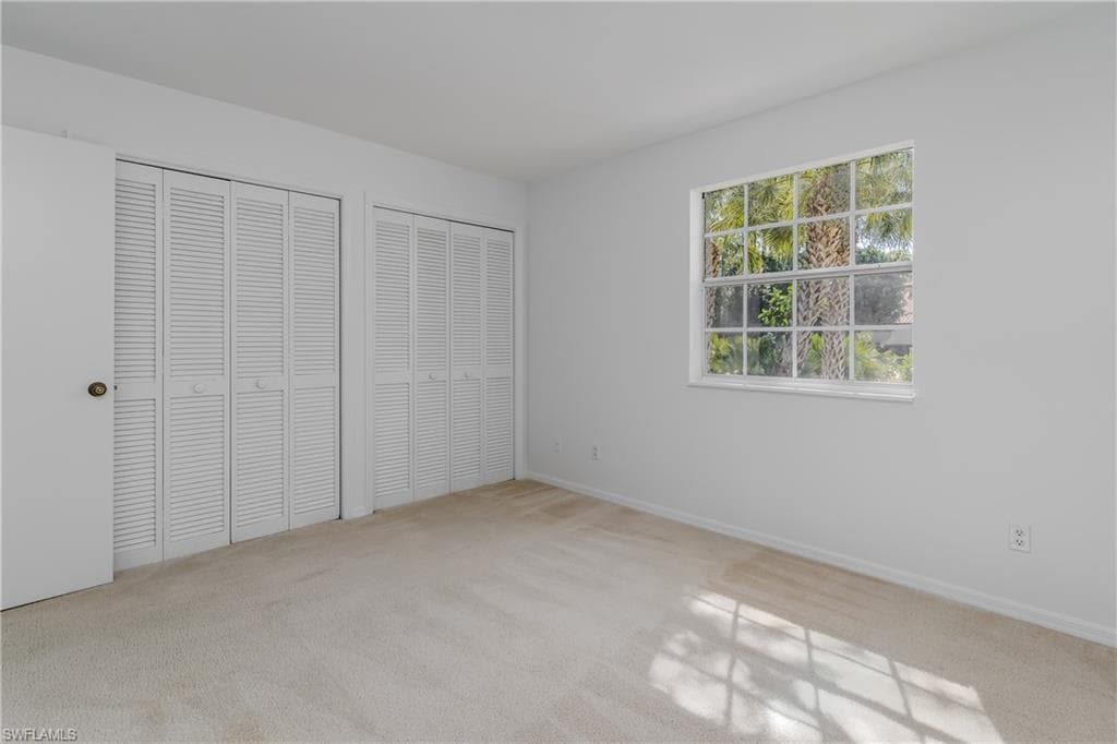 Unfurnished bedroom with multiple closets and light colored carpet