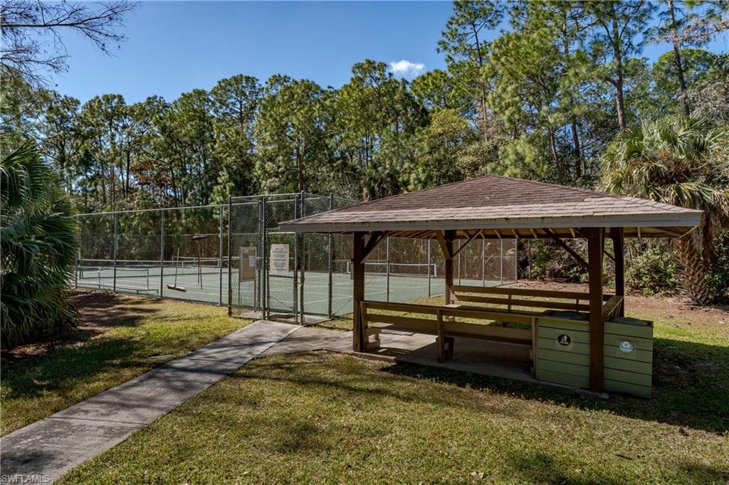 Surrounding community featuring a gate, a tennis court, view of wooded area, and a gazebo