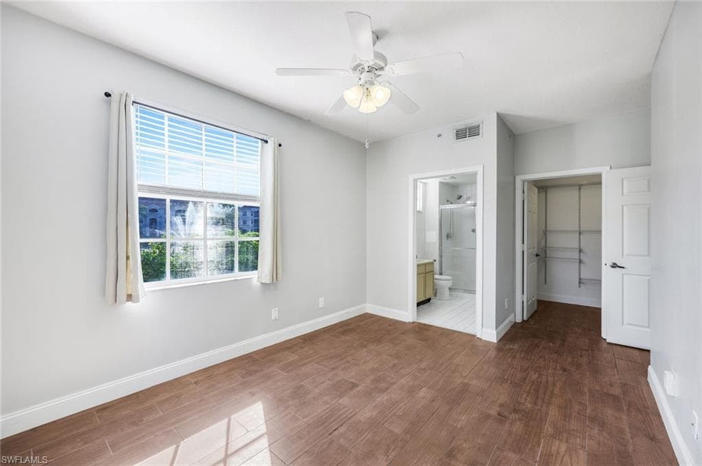 Primary bedroom featuring dark wood-type flooring, a spacious closet, and joining bathroom