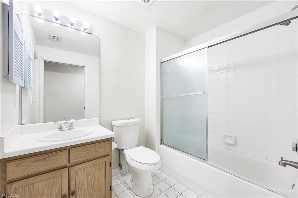 Bathroom with vanity, combined bath / shower with glass door, and light tile patterned flooring