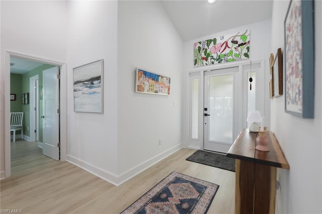 Foyer with light wood finished floors and high vaulted ceiling