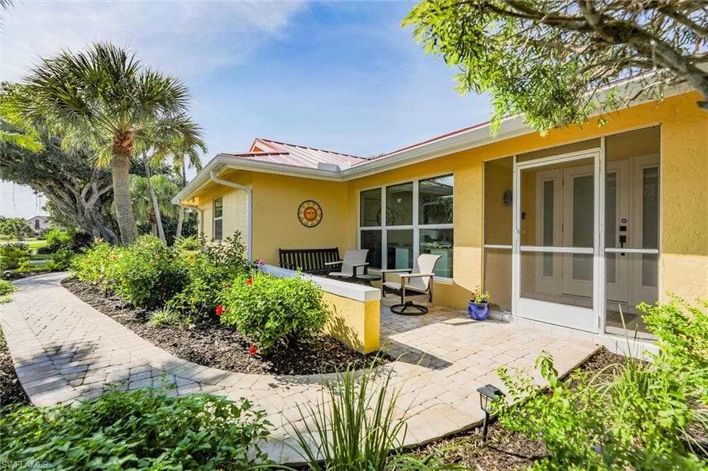 Back of property featuring stucco siding, a sunroom, a metal roof, and a patio area