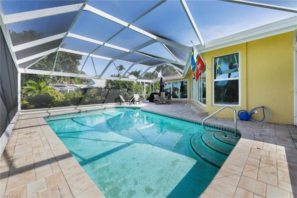 Swimming pool featuring a patio area, a sunroom, and glass enclosure