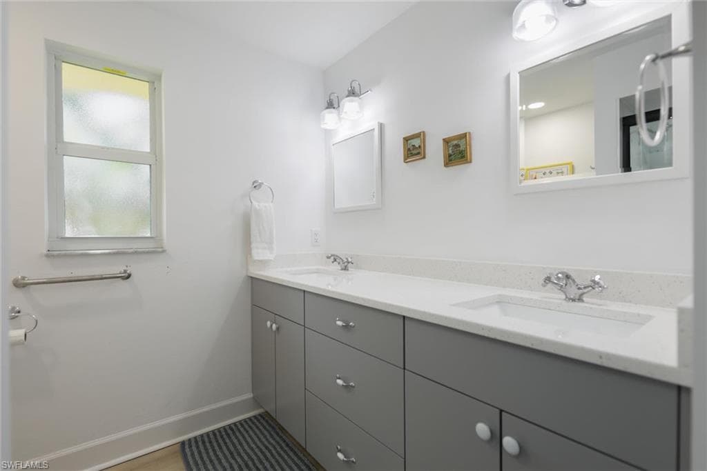 Full bathroom with double vanity and baseboards