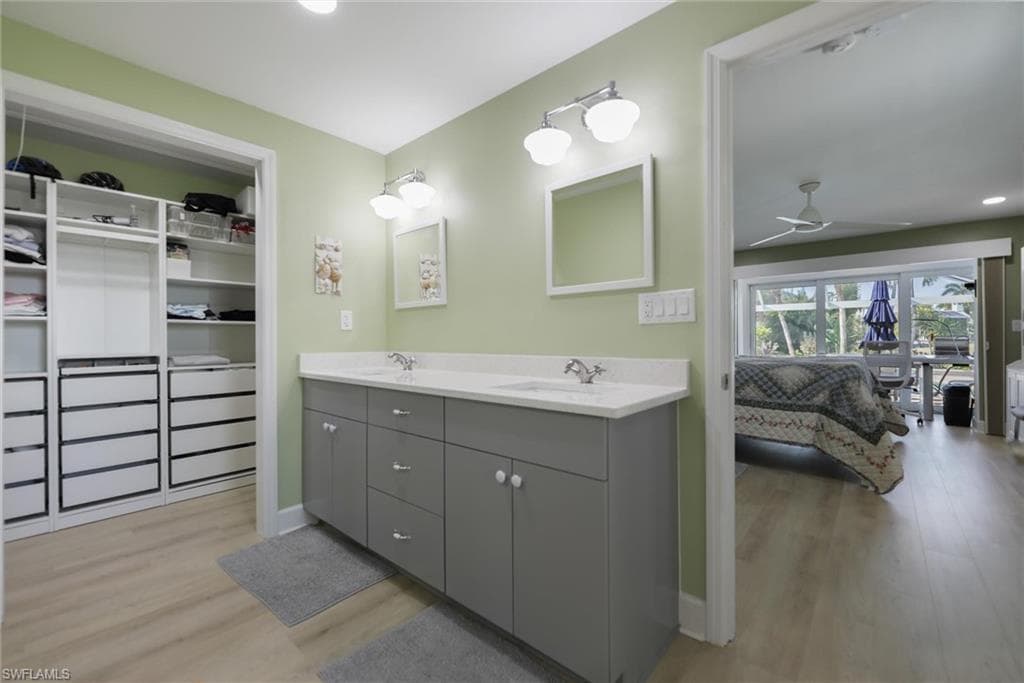 Full bathroom with ceiling fan, double vanity, light wood-style flooring, recessed lighting, and two walk in spacious closets